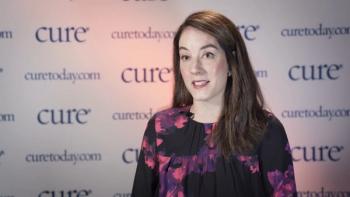 a woman sitting in front of a CURE Background with a black and floral top