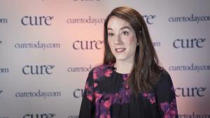 a woman sitting in front of a CURE Background with a black and floral top