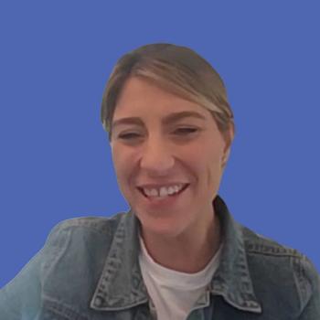 Photo of a woman with blonde hair wearing a denim jacket in front of a blue background