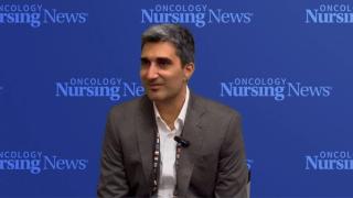 Photo of a man wearing a suit in front of an Oncology Nursing News backdrop