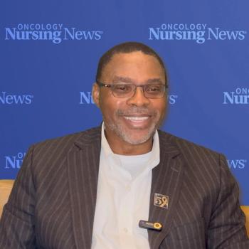 Image of a man in a suit smiling in front of an Oncology Nursing News background