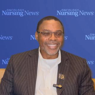 Image of a man in a suit smiling in front of an Oncology Nursing News background