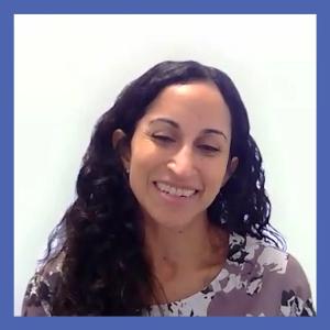 Image of a woman with dark hair wearing a floral shirt in front of a blurred background
