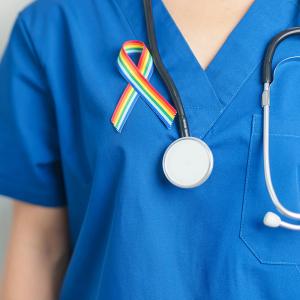 Photo of a nurse wearing an LGBTQIA+ ribbon on their scrubs