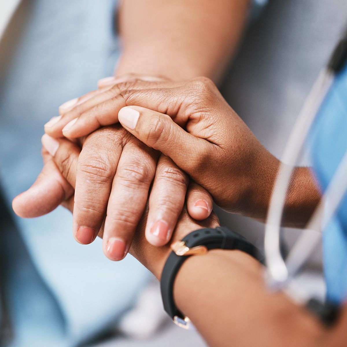 Close-up photo of a patient's hand being held by a the hands of a health care professional