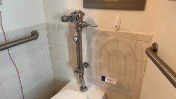 Photo of a hospital bathroom with a Splashblocker toilet seat cover hung on the wall next to it