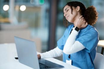 Doctor, laptop and neck pain at night in agony, stressed or burnout by desk at the hospital. Woman medical professional suffering from painful injury, ache or inflammation working late on computer | Image Credit: © C Malambo/peopleimages.com - stock.adobe.com
