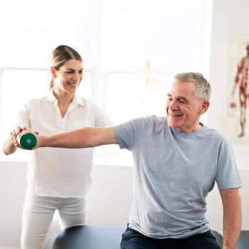 Photo of a man lifting a weight with the help of a trainer