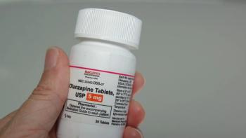 Person's hand holding a prescription bottle of olanzapine
