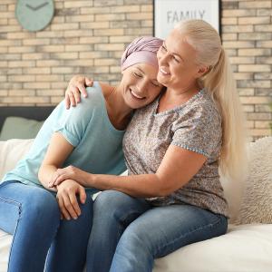 Photo of two women smiling with their arms around each other, one with a headwrap