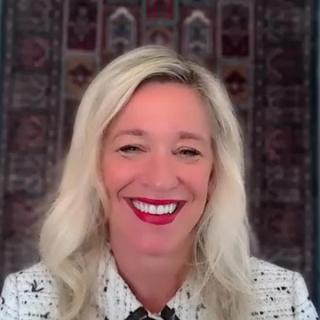 Photo of a woman with blond hair wearing a white and black blazer