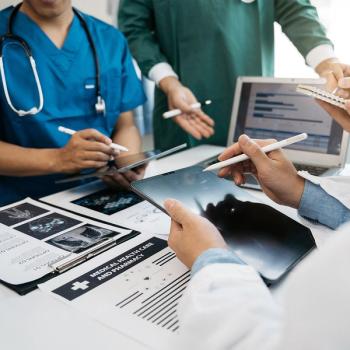 Image of the hands of health care workers with tablets and papers on a table