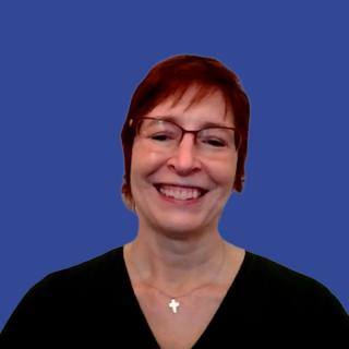 Photo of a woman with red hair and glasses wearing a black blouse and cross necklace in front of a dark blue background