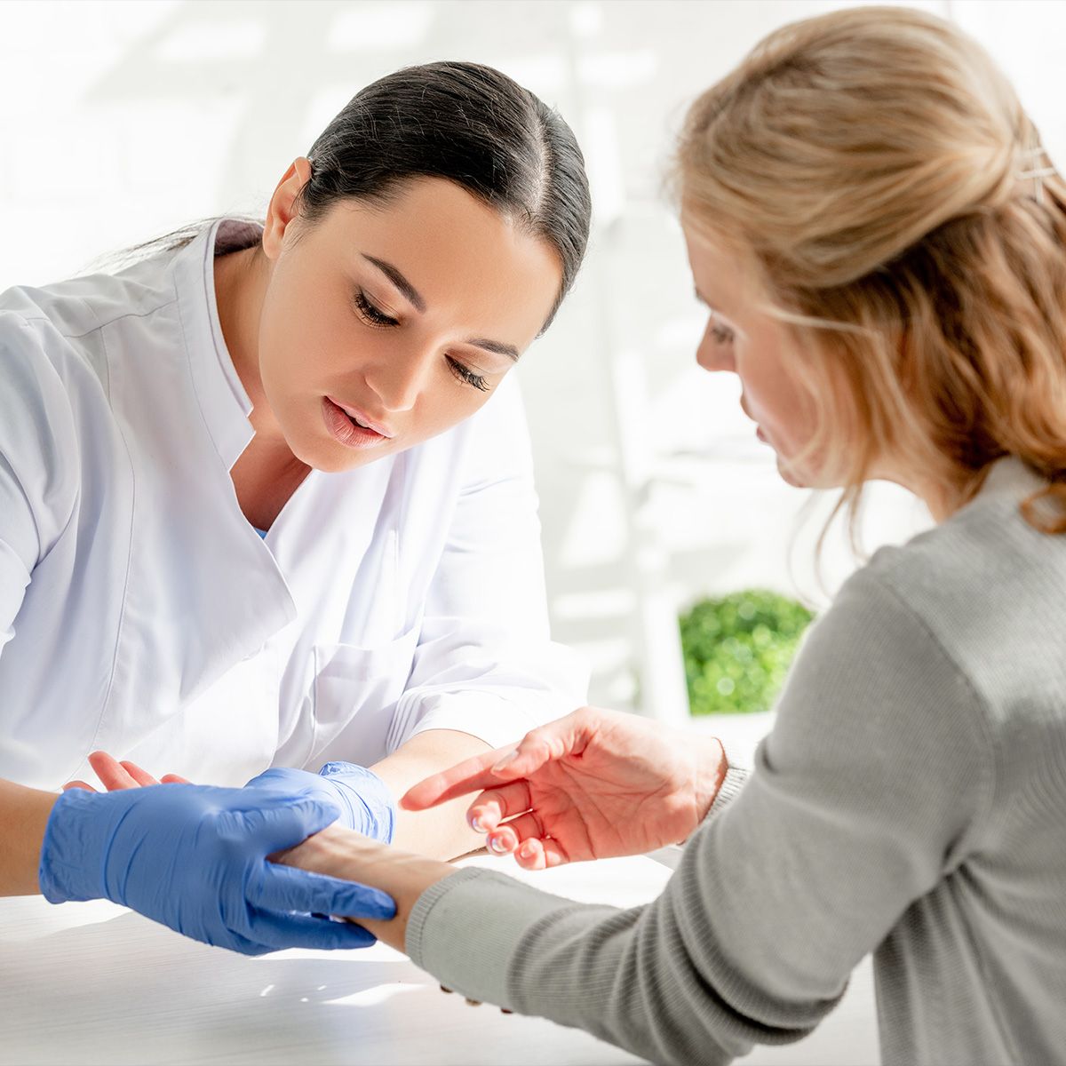 Photo of a person in a lab coat inspecting the arm of a woman