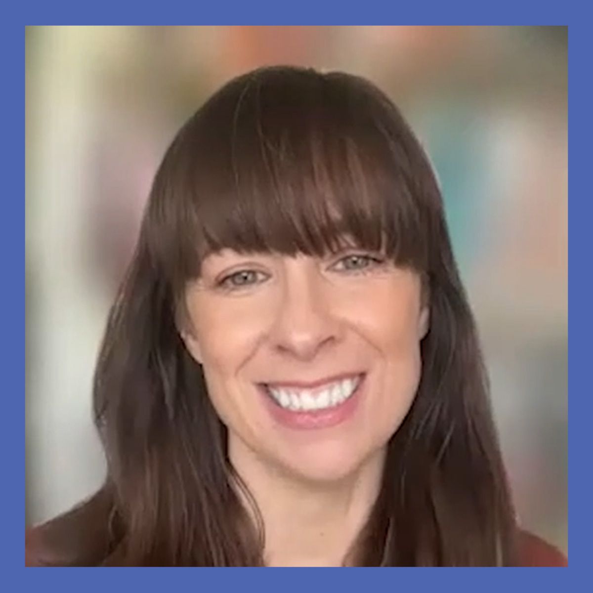 Photo of a woman with brown hair and bangs, surrounded by a blue border