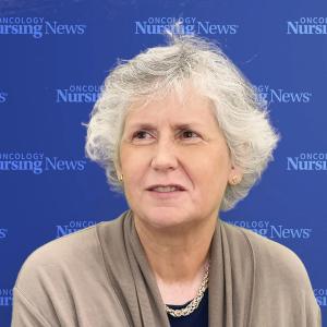 Image of a woman with white hair in front of an Oncology Nursing News blue background