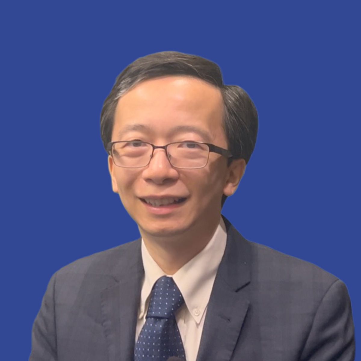 Photo of a man wearing glasses and a suit in front of a blue background