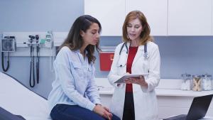 Image of a patient and an APP talking while looking at a tablet in an exam room