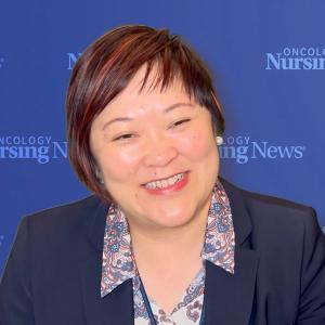 Photo of a woman wearing a blazer in front of an Oncology Nursing News backdrop