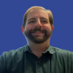 Photo of a man with a beard in front of a blue background