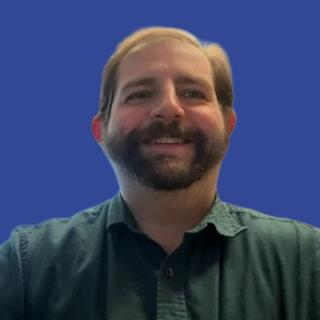 Photo of a man with a beard in front of a blue background