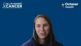 Medium closeup shot of a women in front of a dark blue background with graphics that read "All in Against Cancer" and "Ochsner Health"