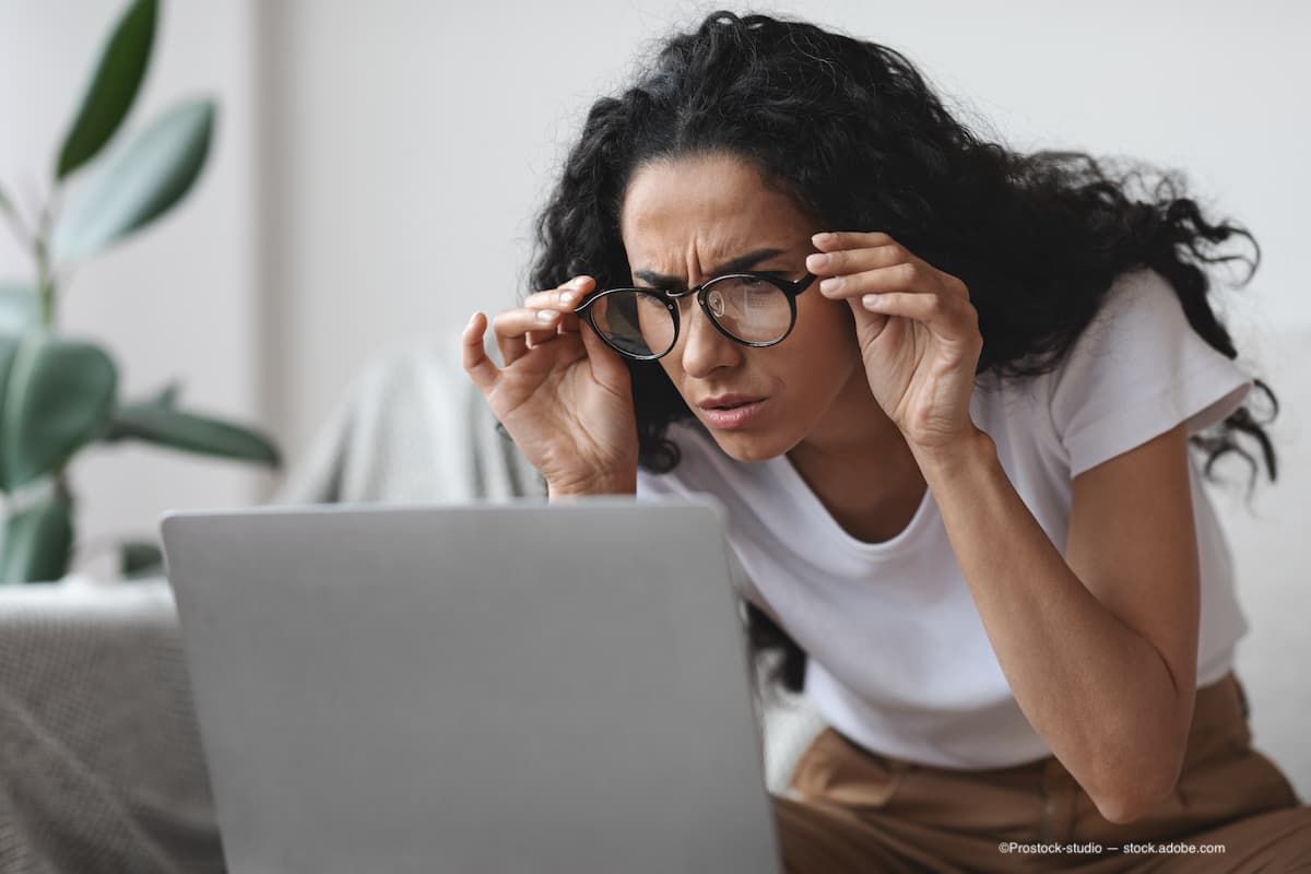 A woman with myopia wearing glasses struggling to read while looking at a laptop