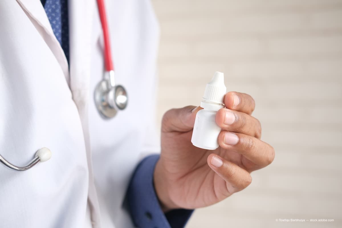 A doctor holding a bottle of eye drops