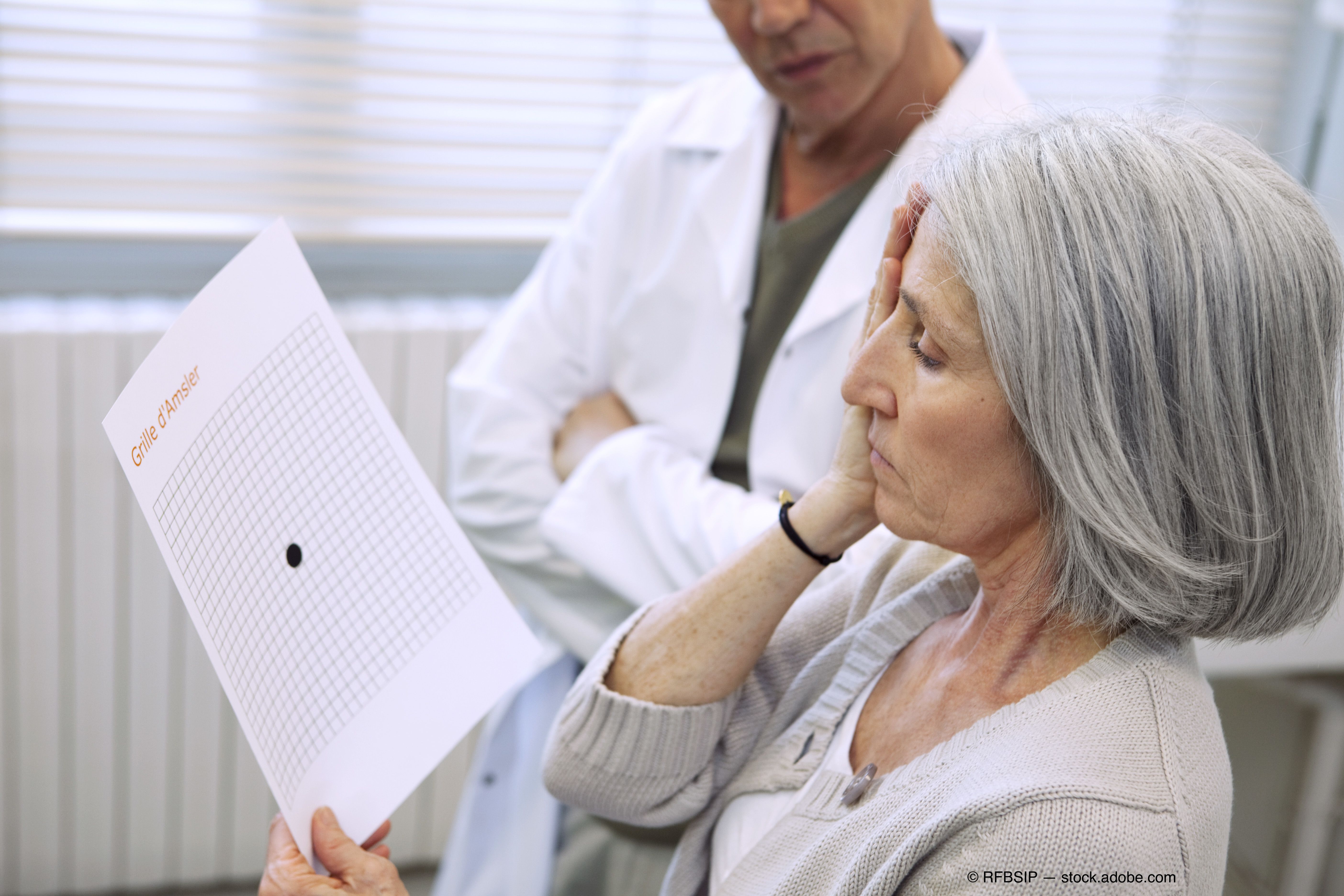 an older woman covers her eye with one hand and and looks at a sheet in front of her in a screening for age-related macular degeneration