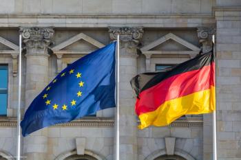 The flags of the European Union (left) and Germany (right), in Berlin, in front of the German parliament. Concept image for European Commission, European Medicines Agency and European myopia atropine drug launch. Image credit: ©respiro888 – stock.adobe.com