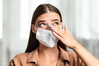 A woman in a surgical mask, covering her nose and mouth, rubs her eyes. Concept image for autoimmune disease correlation to dry eye disease. Image credit: ©Prostock-studio – stock.adobe.com