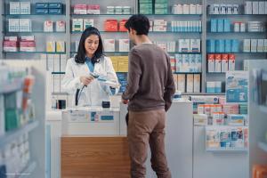 A pharmacist helps a customer access medication. Concept image for neovascular age-related macular degeneration eye drop treatment therapy. Image credit: ©Gorodenkoff – stock.adobe.com