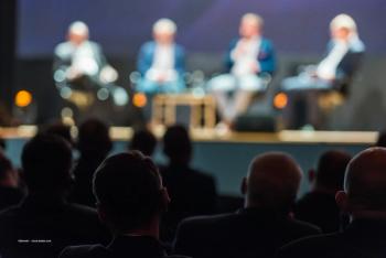 Audience members sit in front of a stage at a conference. Image credit: Image credit: ©Dziurek – stock.adobe.com