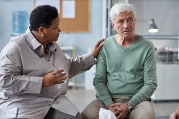 Two elderly patients, a black woman and a white man, in a clinic support each other. Image credit: ©Seventyfour – stock.adobe.com