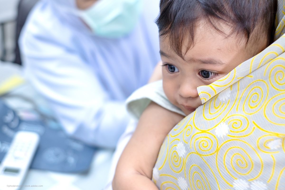 A baby is hugged by their parent in a doctor's office during an exam. Concept image for retinoblastoma diagnosis and treatment, importance of early intervention in paediatric ocular disease. Image credit: ©phoderstock – stock.adobe.com