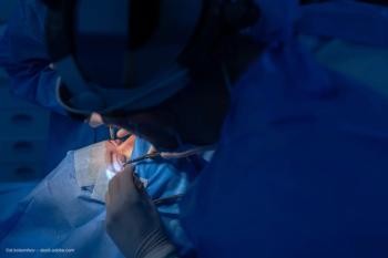 A patient undergoes eye surgery, surrounded by doctors in protective surgical gear. Image credit: ©st.kolesnikov – stock.adobe.com