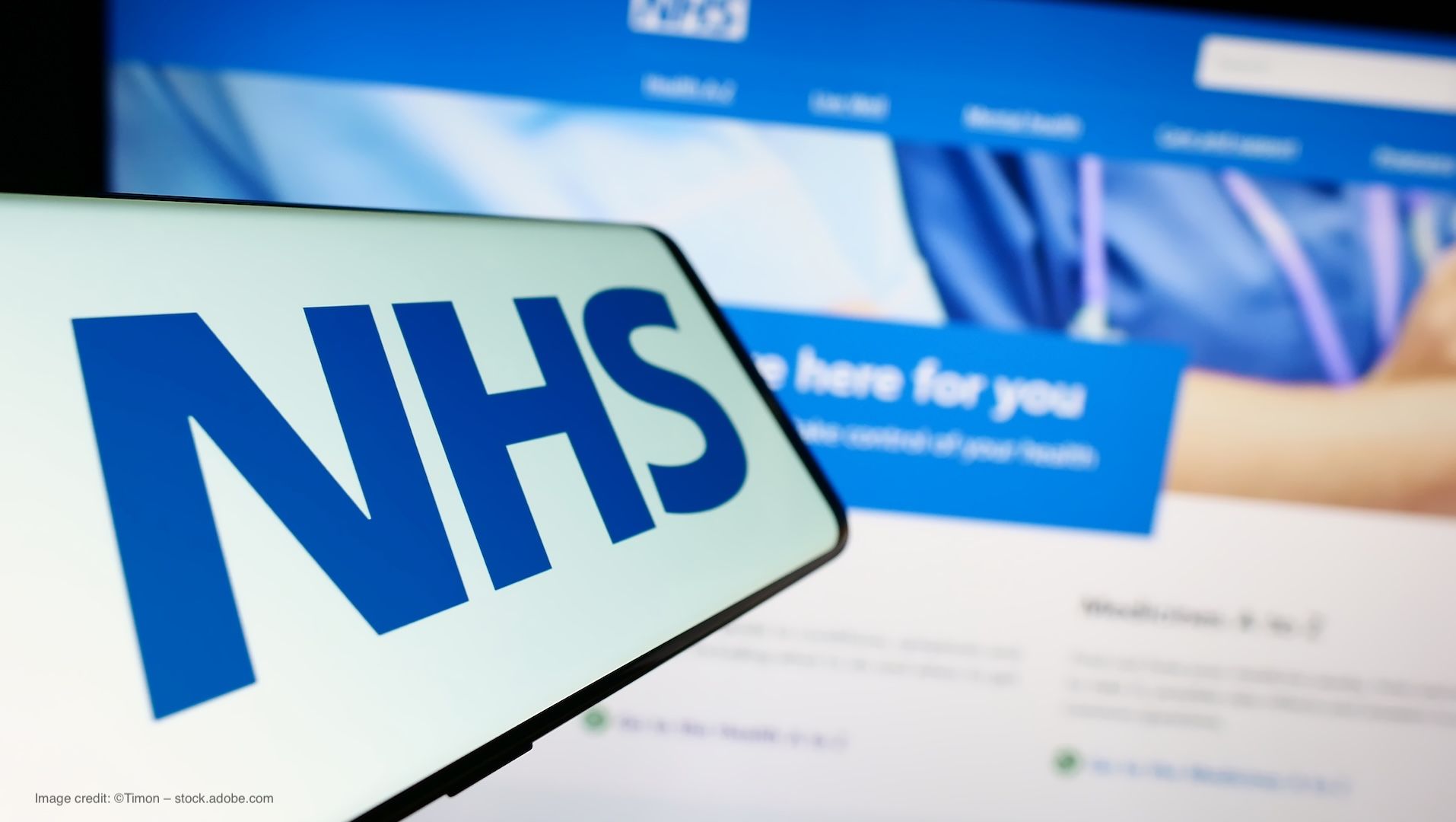 The National Health Service (NHS) logo on a phone, held in front of the NHS website on a computer. Concept image for UK cataract surgery pilot programme, NHS Tayside and Lutra Health collaboration. Image credit: ©Timon – stock.adobe.com