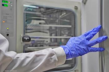 A person in a lab coat and latex gloves opens an incubator in a laboratory. Concept image for innovation and lab incubator. Image credit: ©Panupat – stock.adobe.com