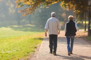 An elderly man and woman walk down a path in a sunny park with grass and trees. Concept image for NICOLA, The Northern Ireland Cohort for the Longitudinal Study of Ageing. Image credit: ©Ivica Drusany – stock.adobe.com