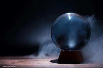 A crystal ball sits on a small platform, surrounded by misty fog. ©alexkich – stock.adobe.com
