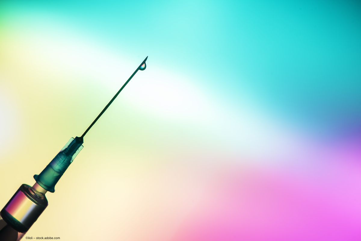 A syringe against a multicolor background, with a drip of liquid at the end of the needle. Image credit: ©iloli – stock.adobe.com