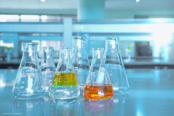A row of beakers with yellow and orange fluid in a laboratory. Concept image for microbial lutein production, bioengineering, sustainable synthesis for cataract cornea age-related macular degeneration (AMD) and retinal disease. Image credit: bidala – stock.adobe.com