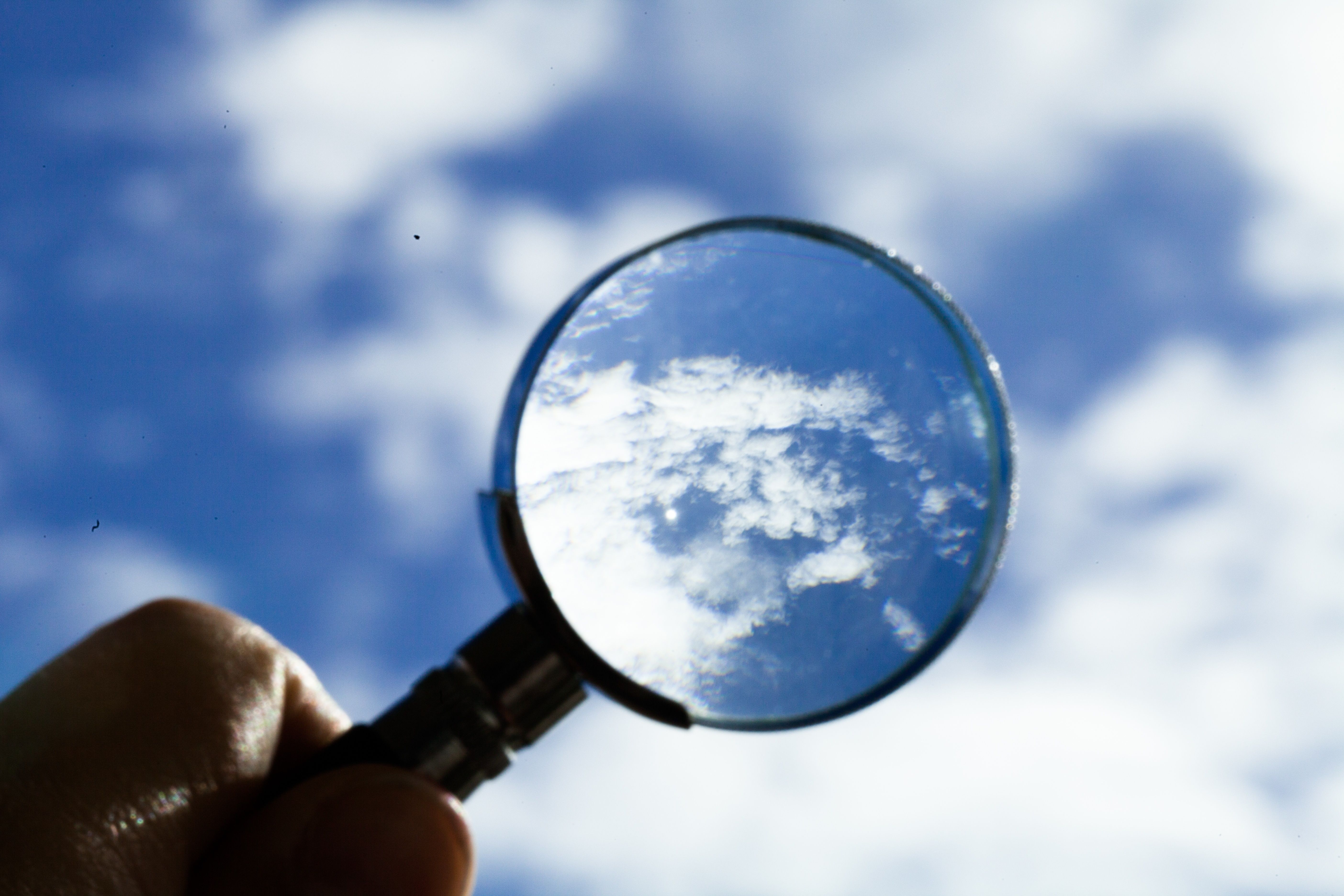 magnifying glass held up to sky for clear vision of clouds