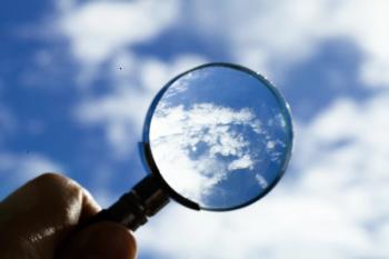 magnifying glass held up to sky for clear vision of clouds