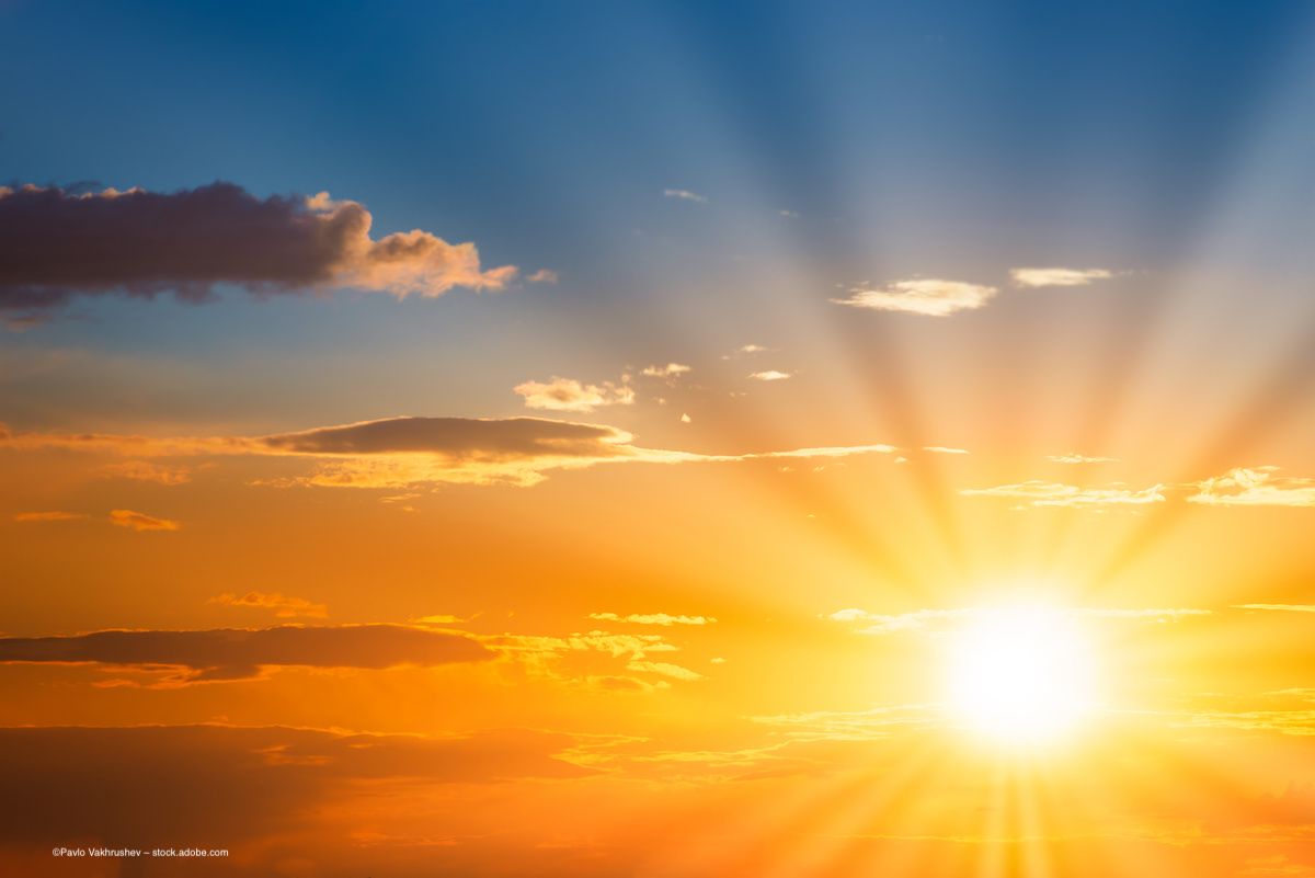 Sun rays stretch over the horizon as a sun rises or sets against a blue sky. Image credit: ©Pavlo Vakhrushev – stock.adobe.com