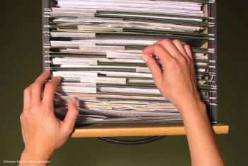 A person's hands are visible as they search in a file cabinet. Concept image for new categorisation of intraocular lens. Image credit: ©Stephen Coburn – stock.adobe.com