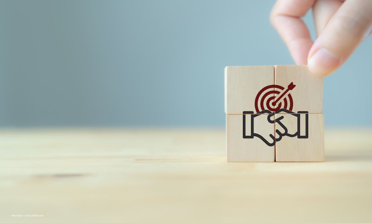 A picture of a handshake and a target on a set of wooden blocks. A person's hand is adjusting the wooden blocks. Image credit: ©Parradee – stock.adobe.com