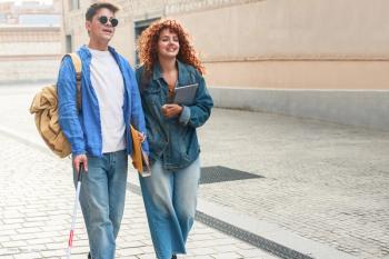 A teen boy or young adult man with a cane and sunglasses is walking happily next to a woman with curly hair. Concept image for NICE approval of Leber hereditary optic neuropathy therapy idebenone. Blindness vision loss and paediatric genetic eye disease. Mitochondrial inherited retinal disease. Image credit: ©Vane Nunes – stock.adobe.com