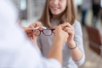 An optometrist hands a paediatric patient her new glasses. Image credit: ©Yakobchuk Olena – stock.adobe.com