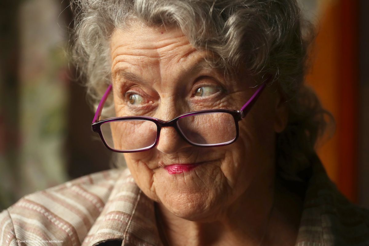 An older woman in glasses, smiling slightly, looks up and to the left. Image credit: ©Pavel Kubarkov – stock.adobe.com